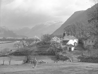 Muž kráčející směrem k cestě a domu Gillerthwaite House, v pozadí jezero a útesy od Joseph Hardman