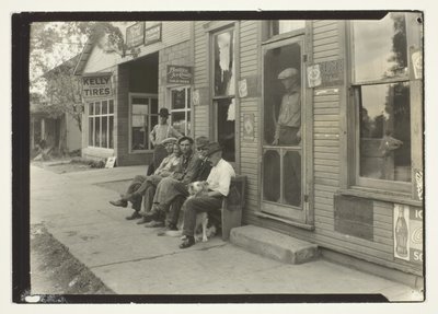 Muži se psem sedící na lavičce před obchodem General Store od Lewis Wickes Hine