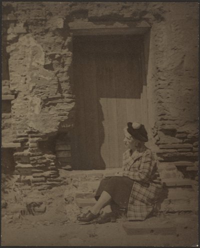 [Žena sedící před chátrající budovou] od Louis Fleckenstein