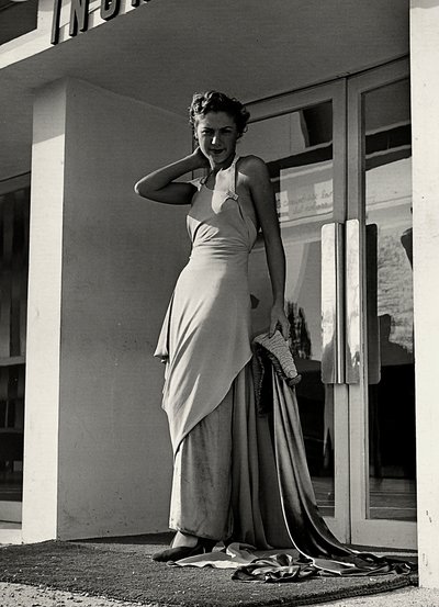 Model ve večerních šatech vytvořený couture house "Graldi". Výrobek se vyznačuje hlubokým výstřihem zdobeným kamínkovými ramínky a dlouhou vlečkou. (černobílá fotografie) od Luis Bogino