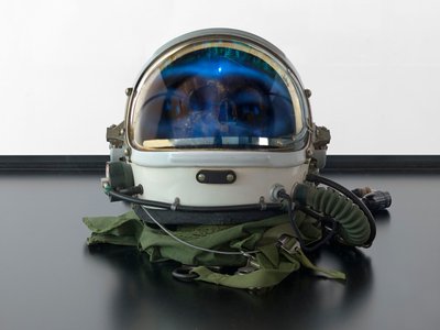 Alpha Omega, 2016 (sklo, LCD displej, přehrávač médií, replika lebky, vesmírná helma, dřevo) od Mat Collishaw