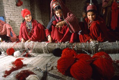 Tkalci a tkalkyně turkmenského kmene upravují uzly na osnově koberce na tkalcovském stavu ve vesnici... od Thomas J. Abercrombie