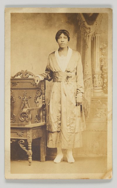 Fotografická pohlednice ženy stojící vedle dřevěné židle, 1904-1918. od Unbekannt