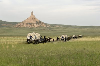 Historie osadníků ze západního Conquete: Američtí průkopníci. Cesty několika rodin přes pláně Spojených států amerických s velkou pílí. Diligence při přechodu skály Chimney Rock na Oregonské stezce v Nebrasce. Barevná rytina kombinovaná s fotografií. od Unbekannter Künstler