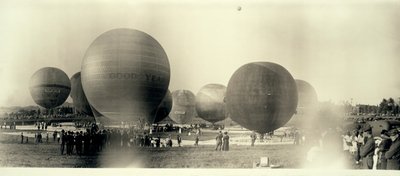 Horkovzdušné balóny na poli v South St. Louis připraveny ke startu; jeden je už na obloze v dálce od W.C. Persons