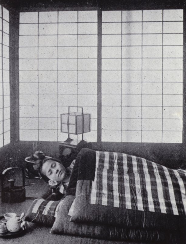 Dívka spí mezi vatovanými přikrývkami s dřevěným polštářem (černobílá fotografie) od American Photographer (after)