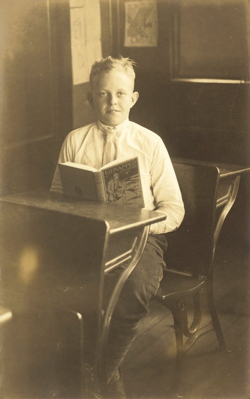 Chlapec čte Unesený (čb fotografie) od American Photographer
