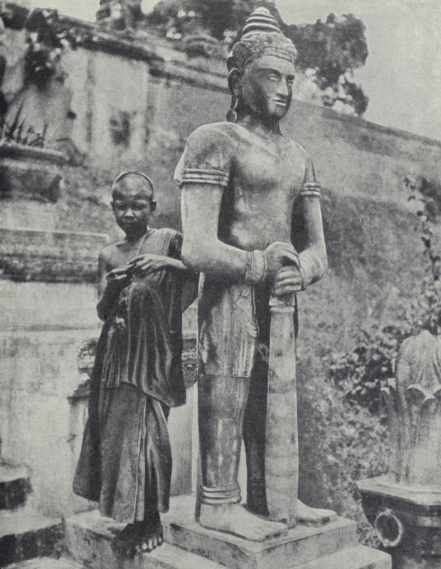 Mladý buddhistický novicový mnich vedle sochy Buddhy, Francouzská Indočína (černobílá fotografie) od Ewing Galloway
