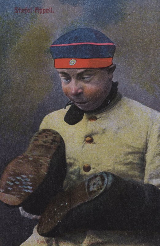 Německý voják při pohledu na podrážky svých bot (barevná fotografie) od Photographer German