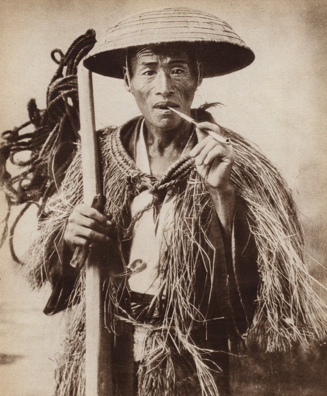 Japonský kuli (farmářský dělník) v klobouku, který ho chrání před prudkým deštěm na rýžových polích (černobílá fotografie) od Photographer Japanese