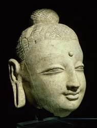 Hlava usmívajícího se Buddhy, řecko-buddhistický styl, z Afghánistánu, 1.-4. století (štuk)