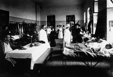 Vyzdobený salon v nemocnici s válečnými raněnými, lékaři, sestrami Červeného kříže a návštěvníky (čb foto)