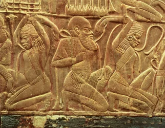 Poražení a zotročení nepřátelé Egypta, detail z vnitřku jednoho ze státních vozů nalezených v Tutanchamonově hrobce (asi 1370-52 př. n. l.) Nová říše, asi 1340 př. n. l. (štukované dřevo pokryté zlatem)