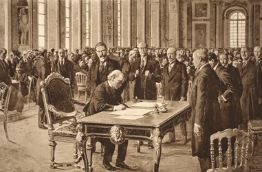 Britský premiér podepisuje mírovou smlouvu s Německem v Zrcadlovém sále ve Versailles, 28. června 1919.
