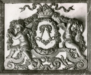 Putti lemující iniciálu L na dveřích Salon des Gardes de la Reine (štukatérské práce)