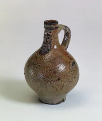 Láhev vína Bartmannkrug nebo Bellarmin zdobená aplikovanou vousatou maskou, Německo, cca 1630-40 (slaná glazovaná kamenina)