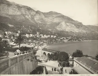 Panoramatický výhled na Montecarlo v Monaku. Scéna ukazuje různé kolemjdoucí; vlevo vidíme detailní záběr na mramorovou balustrádu