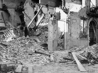 Bombardování Sermida. Dva lidé mezi troskami zničené budovy