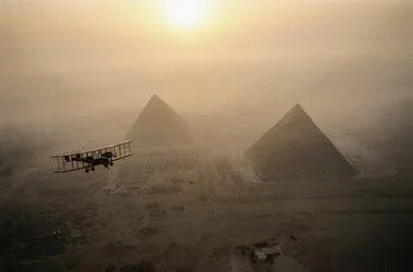 Historický letoun Vimy letí nad mlhou zahalenými pyramidami za zlatého slunce a...