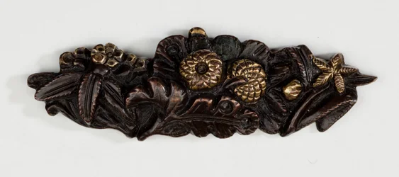 Menuki, neboli gripový ornament, ve formě květinového aranžmá (slitina mědi a zlata se zlacením)