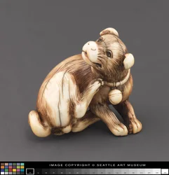 Netsuke modelovaný jako pes, který se škrábe krk