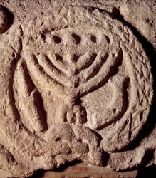 Judaismus: architektonický prvek v čediči synagogy zdobený svícnem se sedmi ratolestmi (Menora nebo Menora), palmou a trubkou. Z Transjordánska. Asi 100 n.l. Paříž, muzeum Louvre