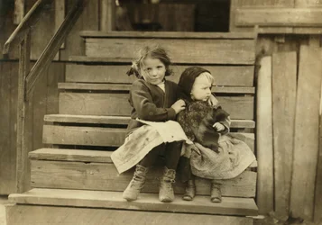 Portrét mladé dívky pečující o malou sestru, zatímco zbytek rodiny pracuje v místní konzervárně, Bayou La Batre, Alabama, USA, kolem roku 1911