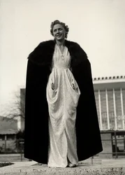 Modelka ve večerních šatech, výtvor módního domu "Graldi". Článek doplňuje pelerína lemovaná kožešinou. (černobílá fotografie)