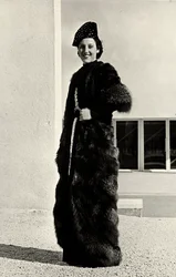 Modelka má na sobě kabát ze stříbrné lišky vytvořený italským couture housem "Dragoni". Soubor je doplněn vyšívaným kloboukem. (černobílá fotografie)