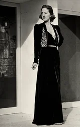 Modelka má na sobě dlouhé večerní šaty z tmavého sametu s vyšívaným zdobením, které vytvořil italský couture house "Fercioni". (černobílá fotografie)