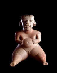 Předkolumbovské umění, mayská civilizace, předklasické období: hliněná soška sedící ženy s oteklým břichem a roztaženýma nohama (rodička?). Z Kaminaljuyú, Guatemala. 19 x 25 cm. Guatemala, Museo Nacional de Arqueología y Etnología