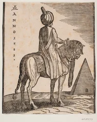 Neozbrojený jezdec v turbanu viděný šikmo zezadu; tj. v pozadí pyramida