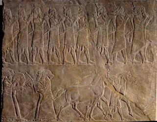 Hudebníci Aššurbanipalské armády. Nízký reliéf ve vápenci kolem roku 640 př. n. l. (neoasyrské období, v. 1000-612 př. n. l.). Objeven v Ninive v Mezopotámii. Muzeum Louvre.