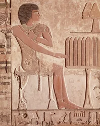 Reliéf zobrazující zesnulého sedícího před obětním stolem s chlebem (malovaný kámen)