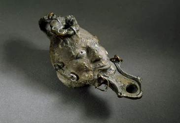 Římské umění: bronzová olejová lampa ve tvaru obličeje. 1. nebo 2. století našeho letopočtu. Španělsko Museo di Ampurias (Empurias)