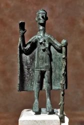 Sardinská nuragská kultura (nuragy): bronzová soška poutníka držícího hůl a zahaleného pláštěm. 8.-7. století př. n. l. Cagliari, Museo Nazionale Archeologico, Sardinie, Itálie