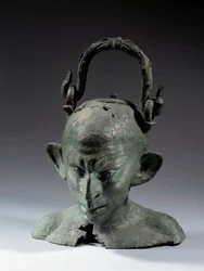 Bronzová váza ve tvaru hlavy: busta syrského otroka (?). 2. nebo 3. století po JC. Ne 0,19 m Paříž, Musee du Louvre