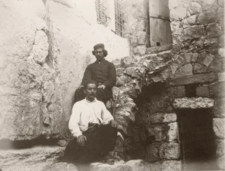 Dva muži sedící u nadpraží Barclayovy brány v Západní zdi Chrámové hory, Jeruzalém, 1866.