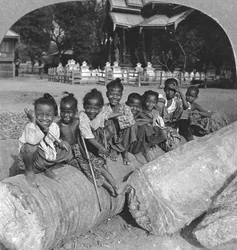 Barmské děti sedící na palmovém kmeni, Barma, 1908