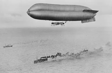 Vzducholoď RNAS Coastal Class C23A letící nad konvojem válečných lodí, cca 1917