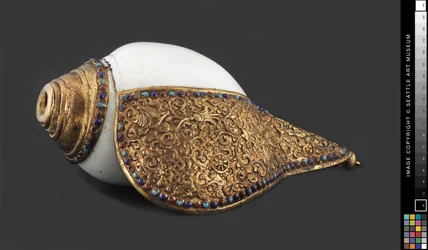 Buddhistická rituální mušlová trubka, kolem 1750-1850 (ulita lastury, pozlacená měděná slitina, polodrahokamy)