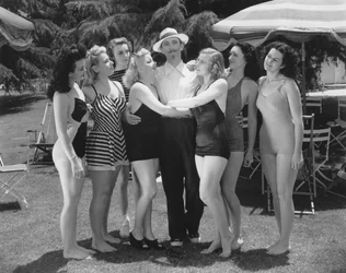 Hollywood, Kalifornie: kolem roku 1935 Sedm mladých žen v plavkách soupeří o pozornost jediného muže. (černobílá fotografie)