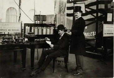 Lee DeForest (sedící) posílá zprávu bezdrátového telefonu v ministerstvu elektřiny na světové výstavě v roce 1904