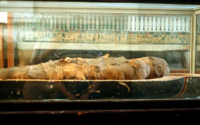 Mumie zabalená do obvazů a ležící na podstavci rakve, starověký Egypťan