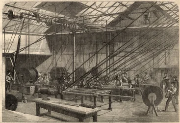Telegrafie: výroba transatlantického kabelu. Stroje na potahování gutaperčového kabelu v továrně Glass, Elliot and Company na Wharf Road v Londýně, Anglie. Rytina do „“The Illustrated London News““ ze 14. března