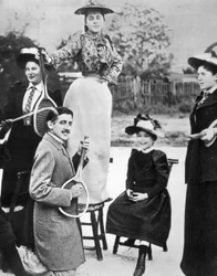 Marcel Proust, uprostřed skupiny mladých žen, hrajících na kytaru na tenisové raketě na Bineau Boulevard v Paříži