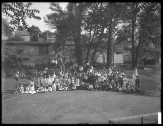 Velká skupina dětí se sešla pro skupinový portrét na neidentifikovaném hřišti, kolem roku 1910